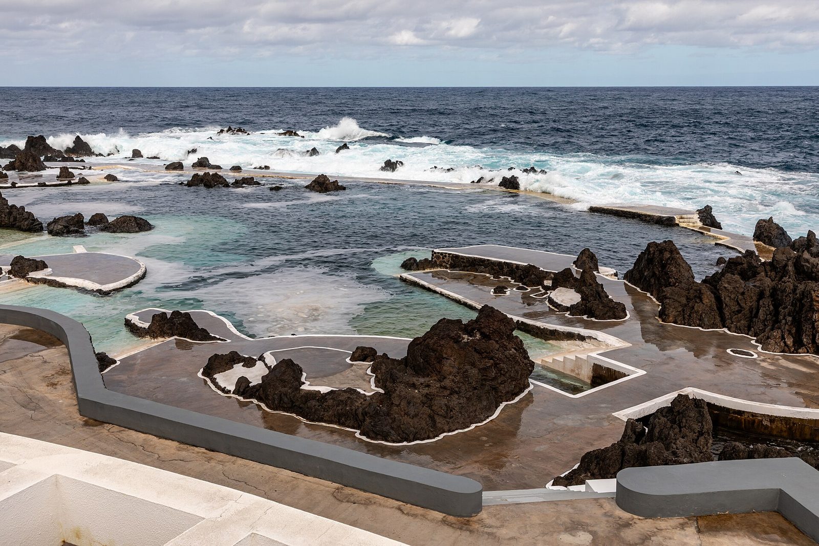 Turquoise volcanic swimming pools surrounded by black lava rock at Porto Moniz