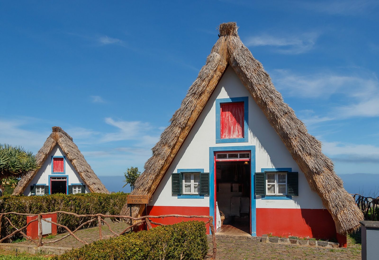Traditional triangular thatched houses with red doors at Santana