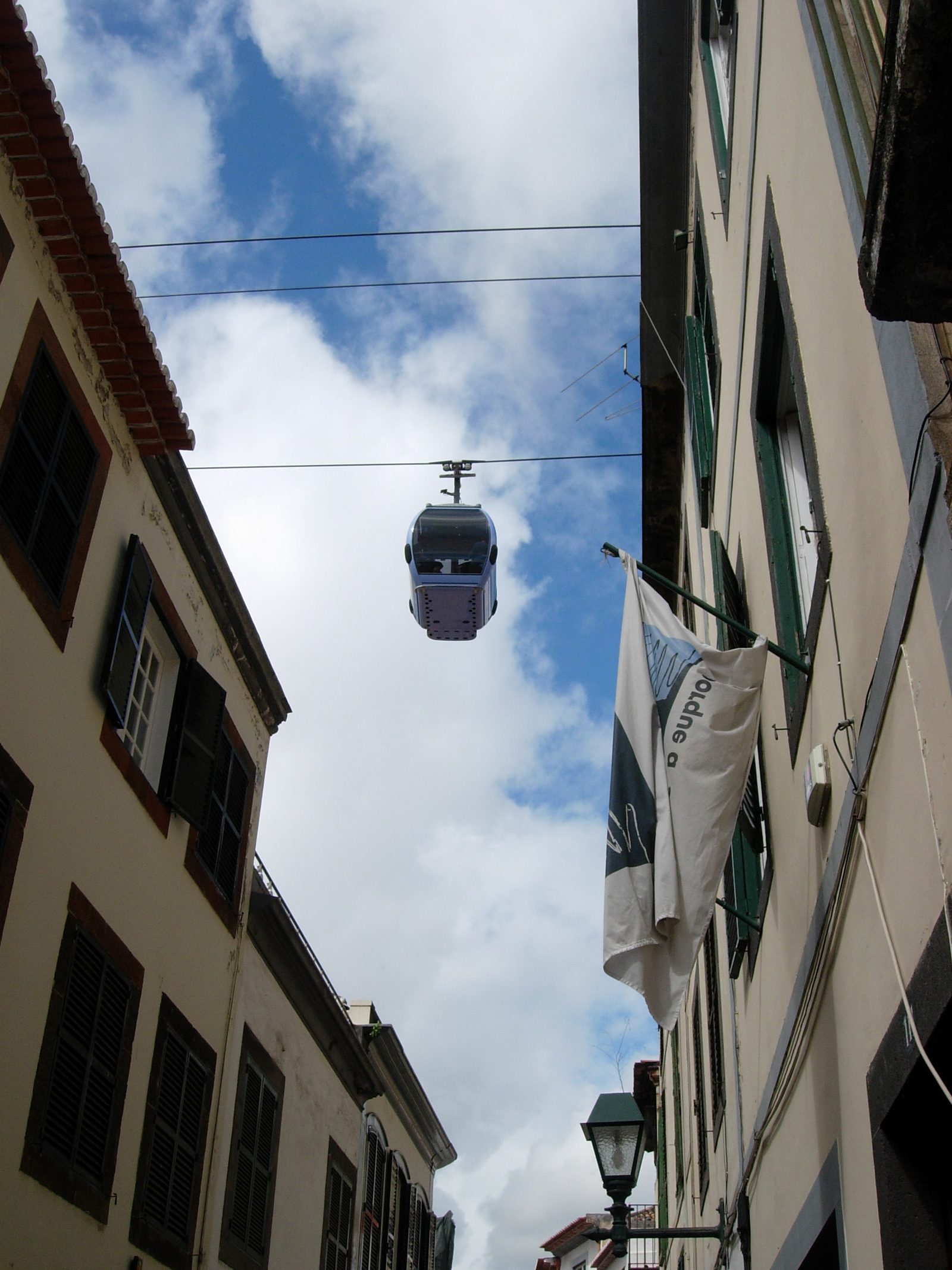 Cable car cabin rising above Funchal's rooftops towards Monte